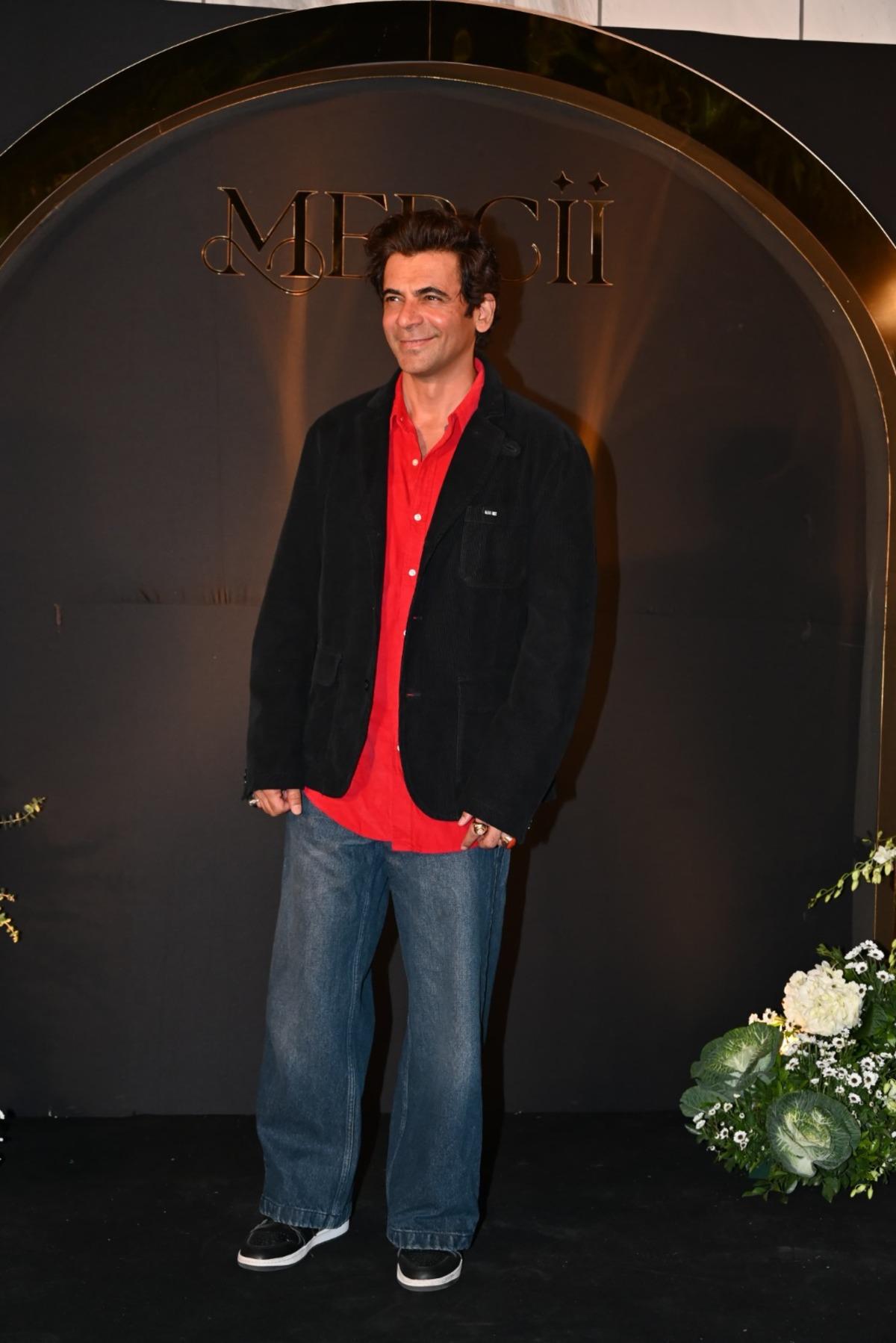 Sunil Grover was seen in a red shirt with a black jacket and paired it with blue denims.