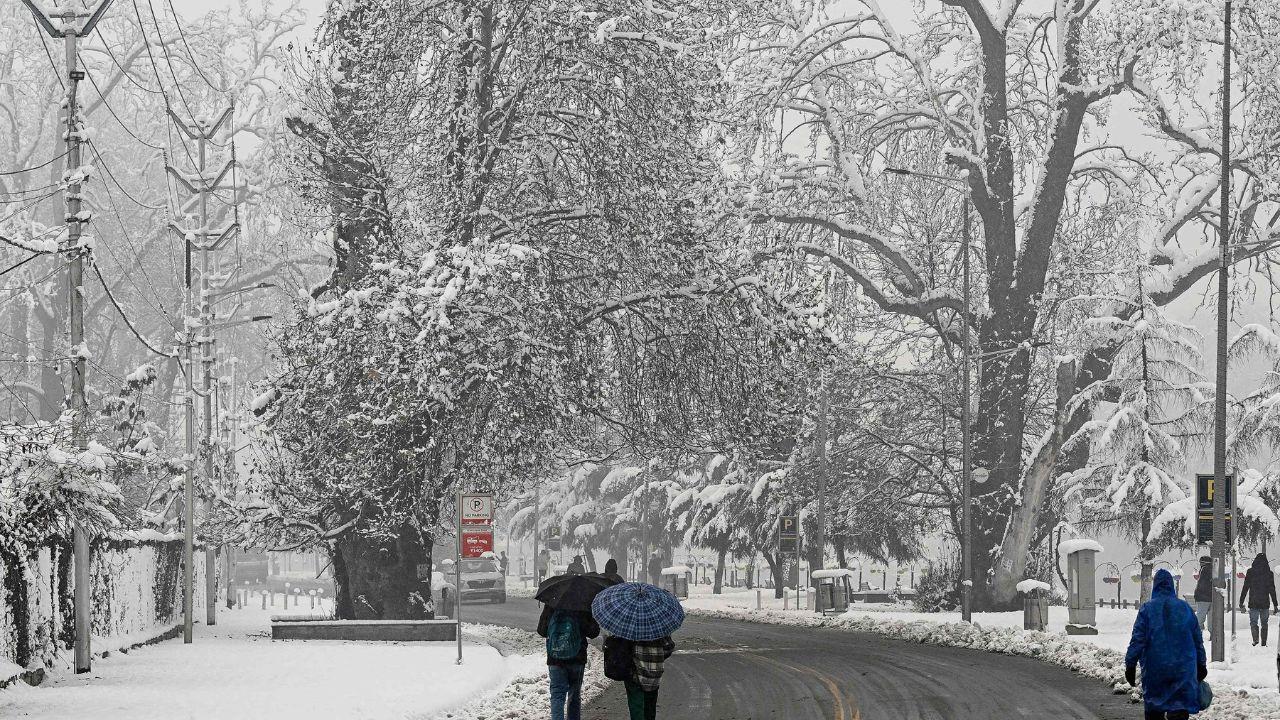 People walk along a road after winter's first snowfall in Srinagar. (Pic/ AFP)