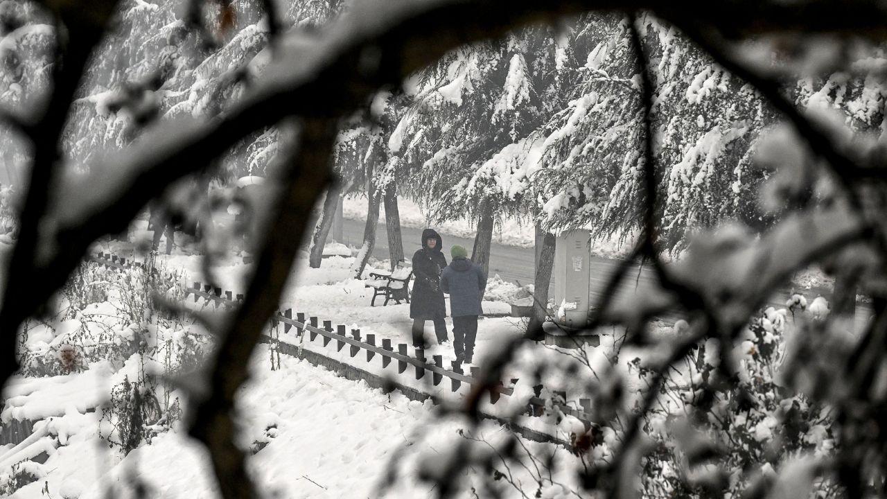People walk through a snow-covered road after winter's first snowfall in Srinagar. (Pic/ AFP)
