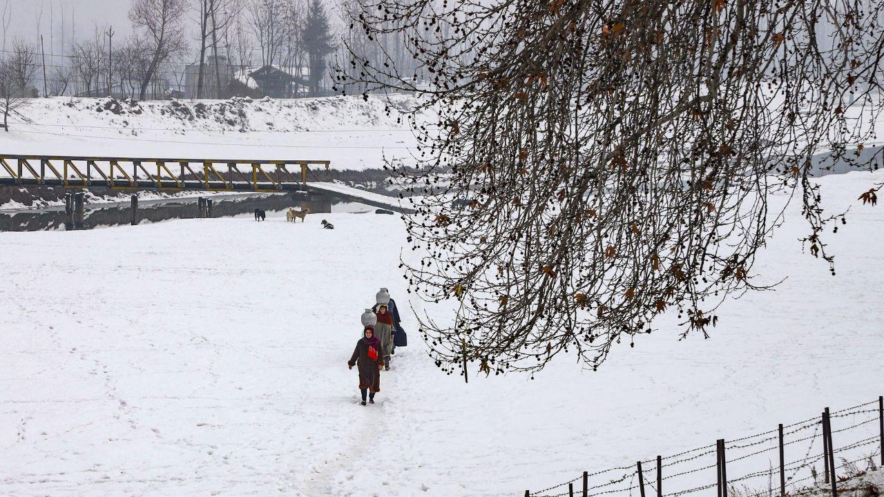 Women carry utensils to fetch water as the area faces water shortage after heavy snowfall, on the outskirts of Srinagar. (Pic/ PTI)