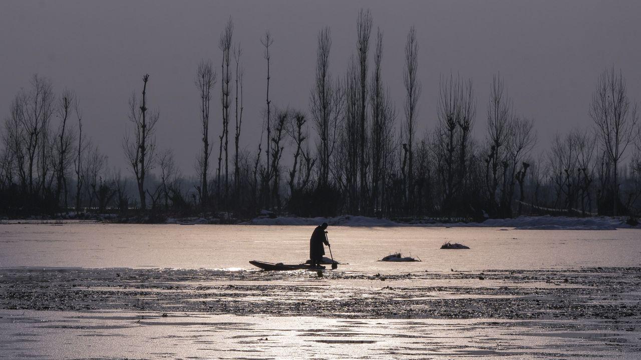 A man rows a boat on the icy water of Dal Lake after snowfall, in Srinagar. (Pic/ PTI)