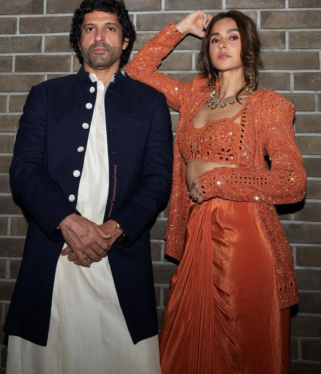 Farhan Akhtar opted for a white kurta-pyjama paired with a blue sherwani, while Shibani complemented him in a contrasting orange outfit, striking the perfect balance between comfort and ethnic vibes