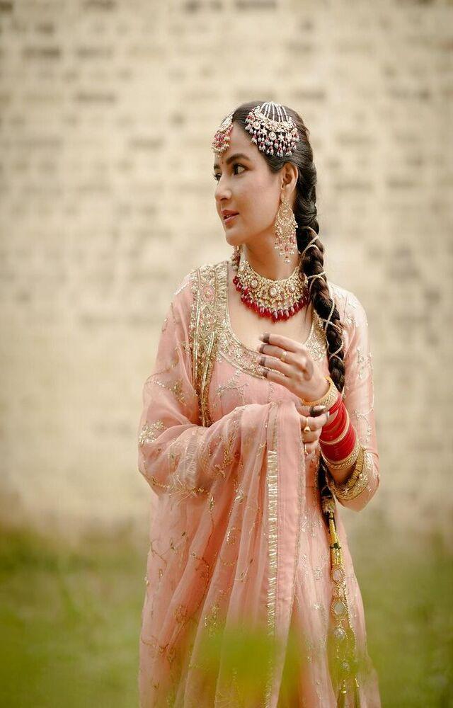 Jasmin decked up from head to toe in jewellery which includes a choker set, maang tika, as well as a red choora with kaleeras
