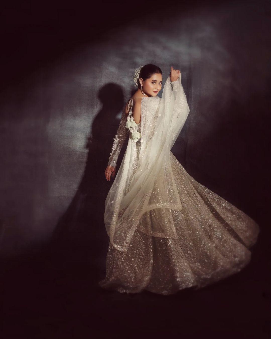 Rashami's style takes a turn with a white Anarkali kurta set, exuding grace and sophistication. The heavily decorated kurta paired with a sheer dupatta creates a striking visual