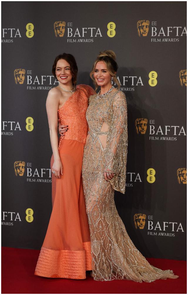 Emma Stone and Emily Blunt (R) pose on the red carpet upon arrival at the BAFTA British Academy Film Awards