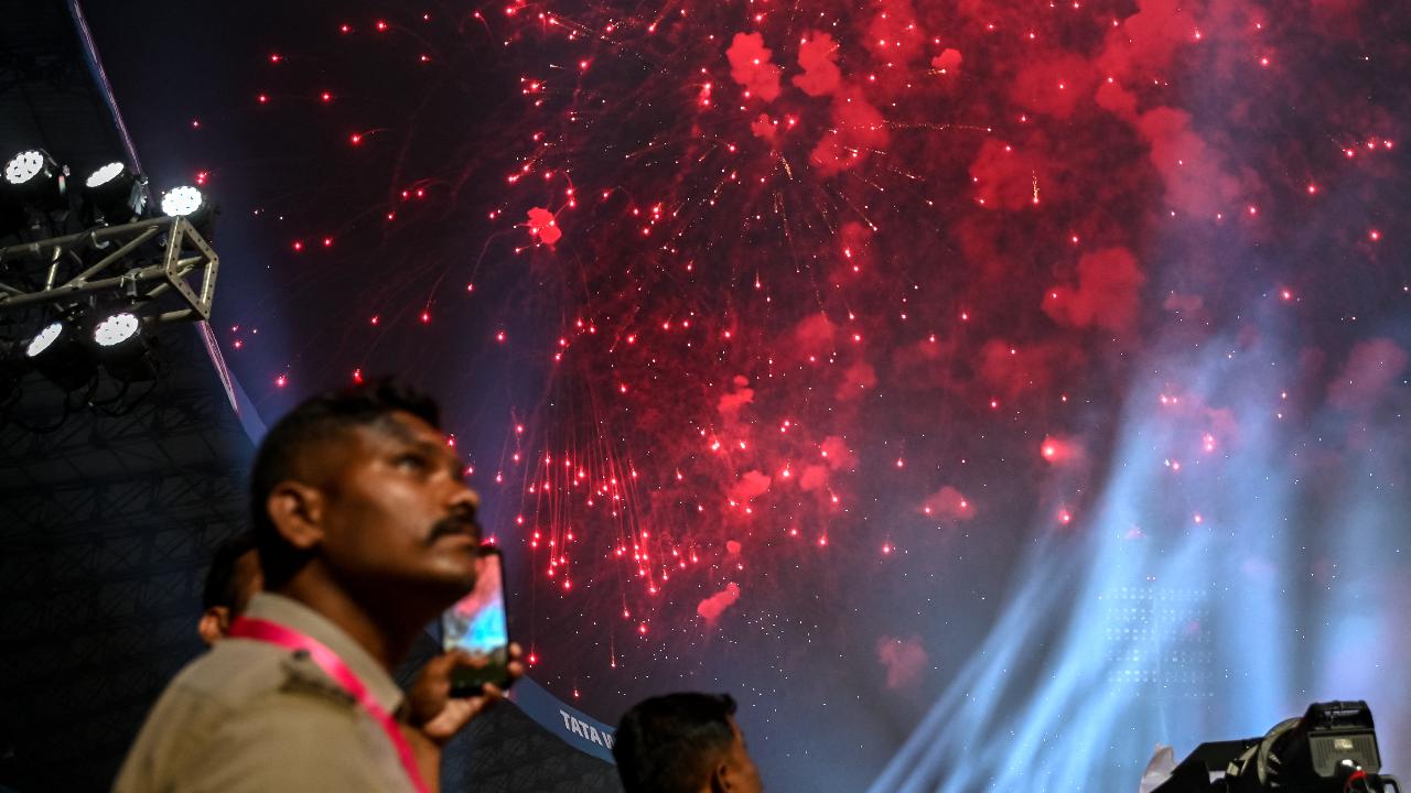 Police personnel watch the fireworks during the 2024 Women's Premier League (WPL) Twenty20 cricket match between Mumbai Indians and Delhi Capitals