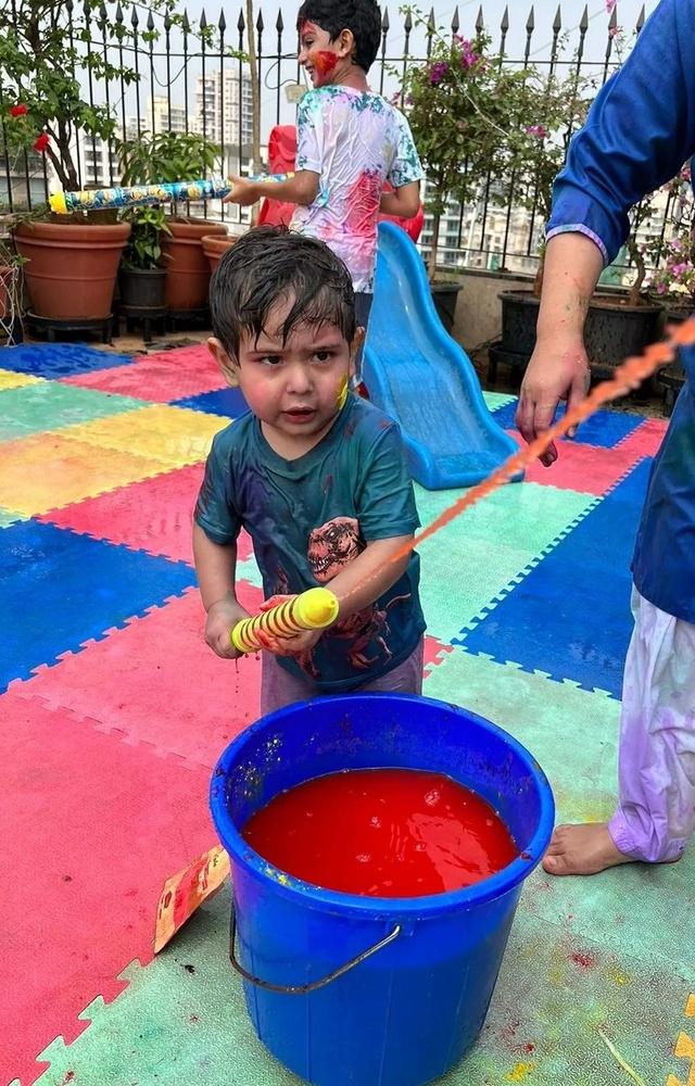 Keeping up with festivities, Jeh holds a water gun, about to splash during their Holi celebration
