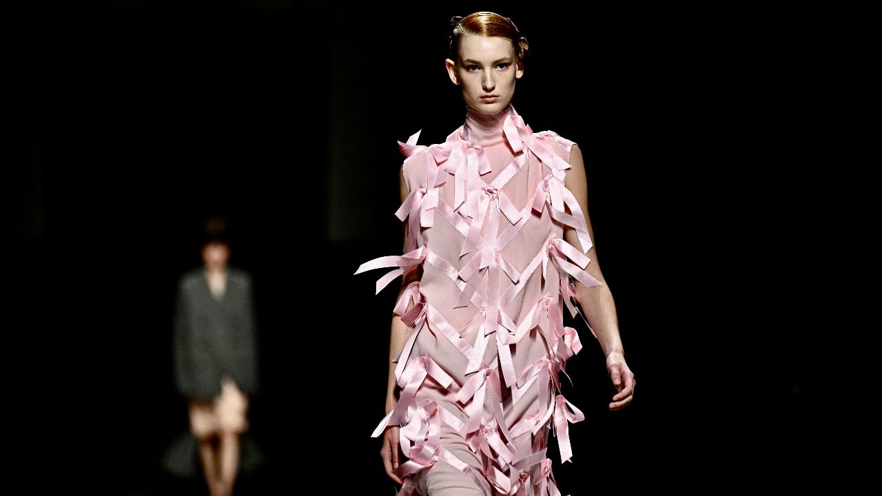 Strips of silk satin cascade from a mud pink body-hugging fit as a model walks the runway during the Prada collection