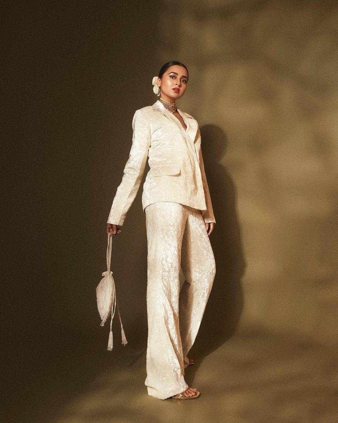 Let's talk about Tejasswi's outfit, and how perfect it is for Promise Day – it's a classy off-white colour. She has her hair tied up in a knot with a side partition and holds a matching off-white handbag. 