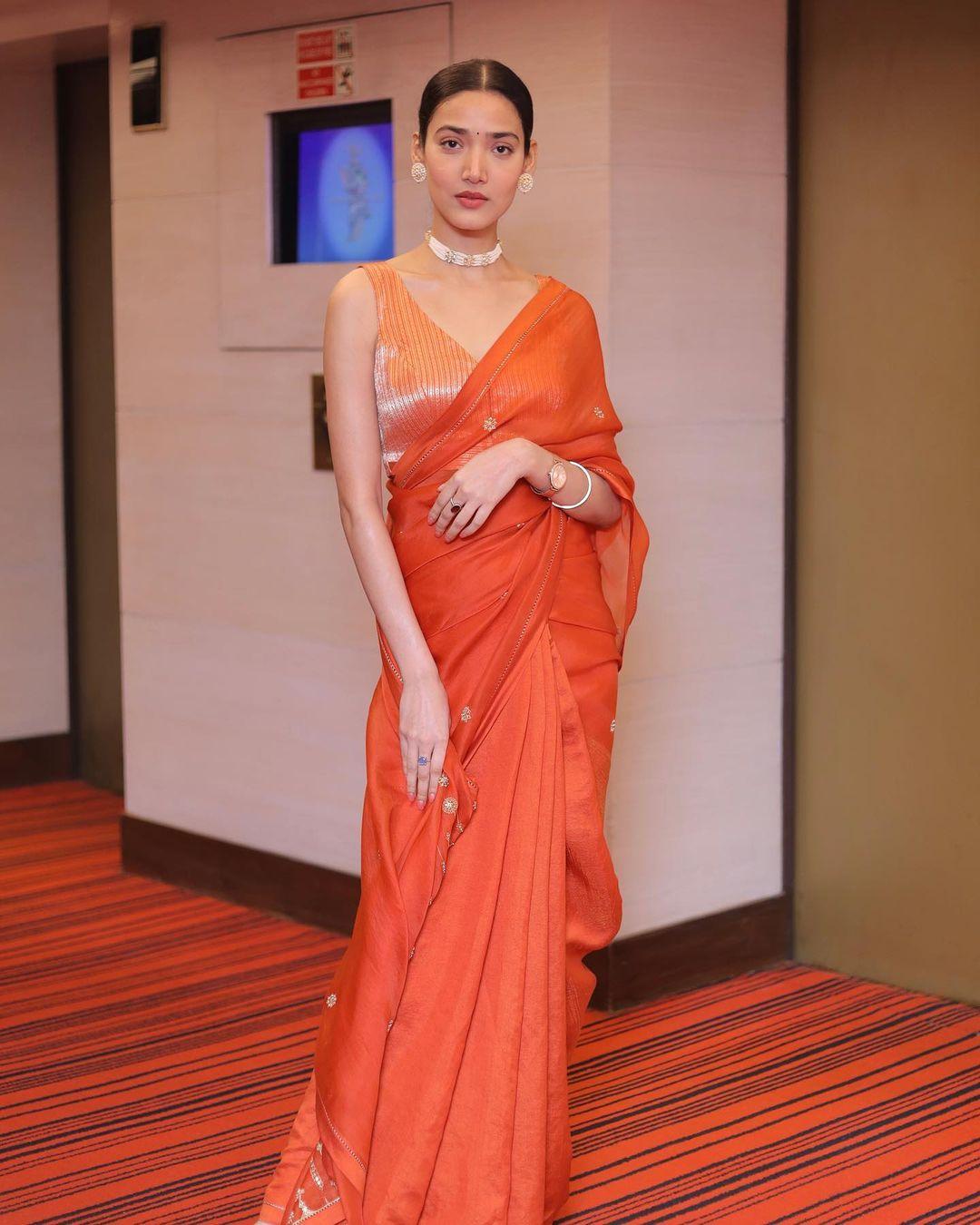Medha shines in an organza saree in vibrant orange, paired with a matching blouse
