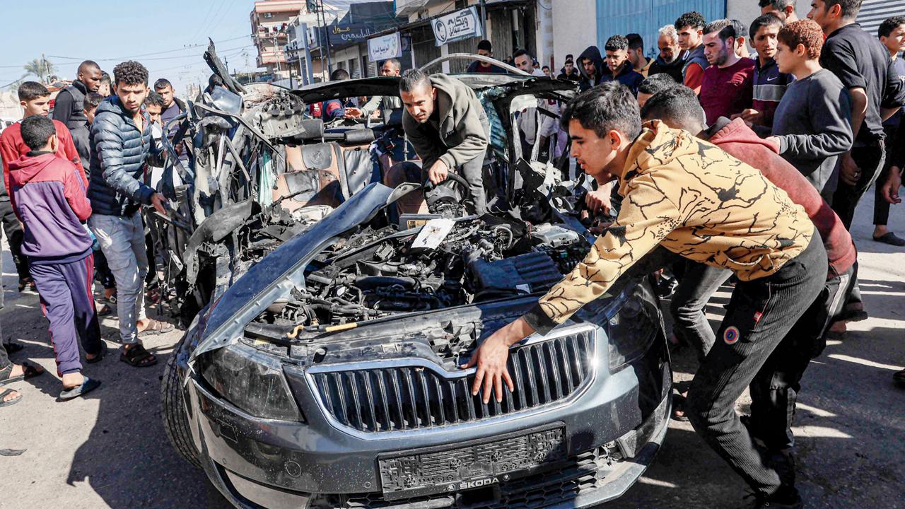 People check the car in which two journalists were killed in Rafah
