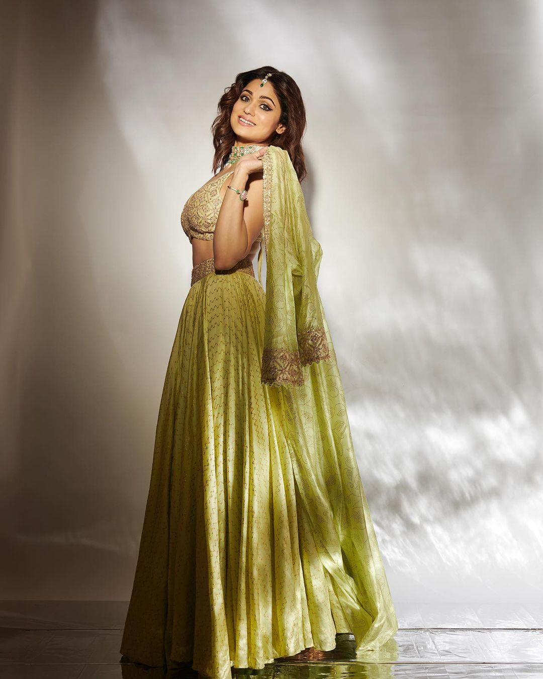 Paired with a white embroidered blouse and matching palazzo, she accessorizes with a jhumka and intricate green necklace