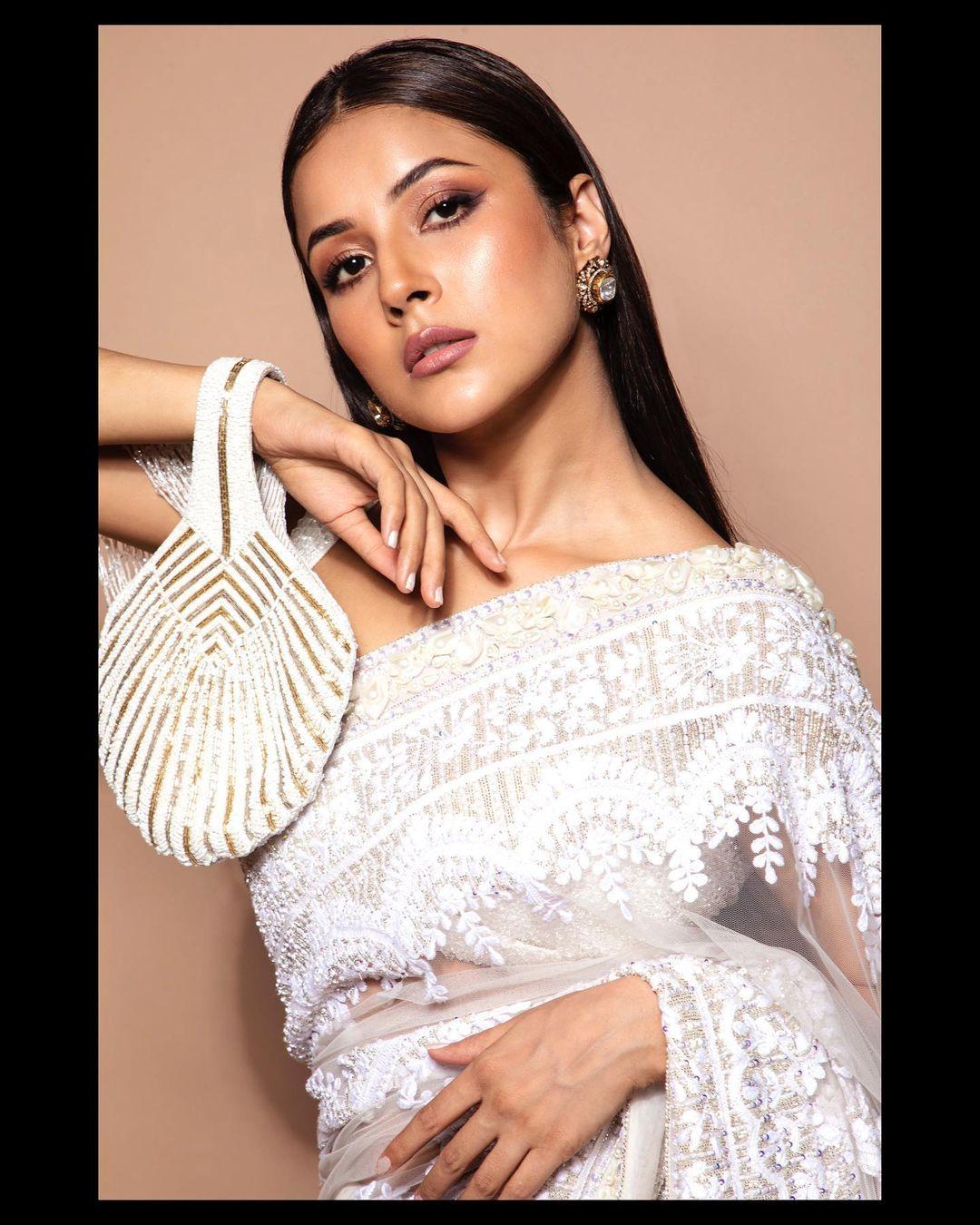 The cold-shoulder blouse complements the ensemble, while her sharp contour and subtle nude makeup enhance the grace