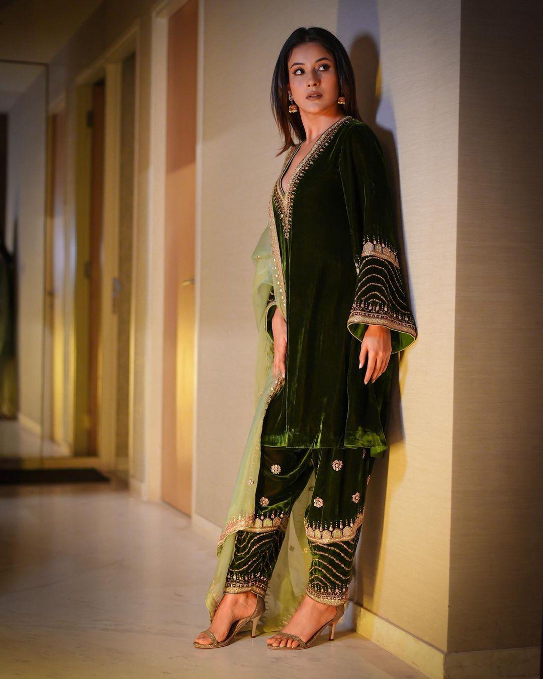 Shehnaaz effortlessly achieves a chic look in a dark green velvet outfit adorned with a captivating border. The contrasting neon-colored dupatta adds a playful twist, injecting vibrancy into the ensemble