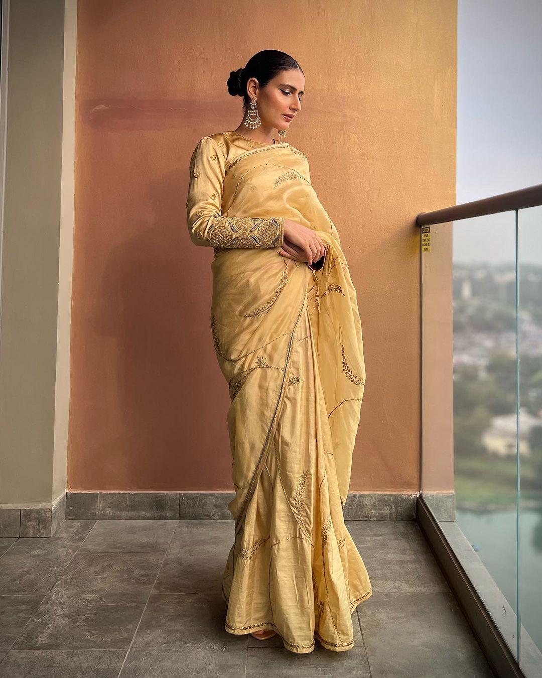 Fatima Sana Shaikh looks absolutely stunning in a golden saree that's just perfect for Lohri celebrations. The full sleeves and her hair styled in a bun add an extra level of style to the saree. The long jhumkas she's rocking perfectly match the richness of the golden saree