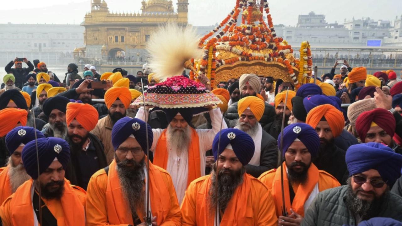 Sikh holy men known as 'Panj Pyare' hold swords as they escort a priest (C) carrying the Sikh holy book 'Guru Granth Sahib' during a religious procession on the occasion of the birth anniversary celebrations of the tenth Guru of the Sikhs, Guru Gobind Singh, at the Golden Temple in Amritsar