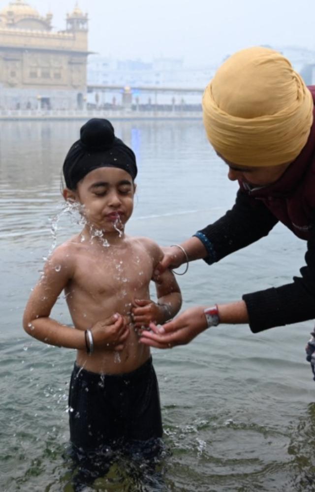 A young Sikh devotee takes a bath in the holy Sarovar (pool) at Golden Temple in Amritsar