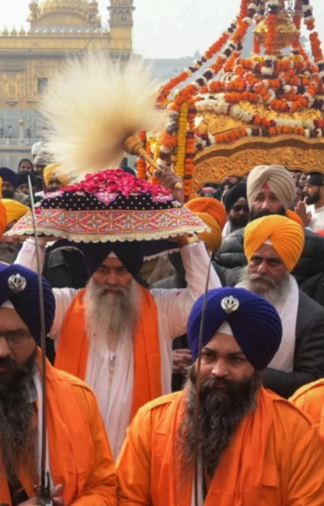 Sikh holy men known as `Panj Pyare` hold swords as they escort a priest (C) carrying the Sikh holy book `Guru Granth Sahib` during a religious procession