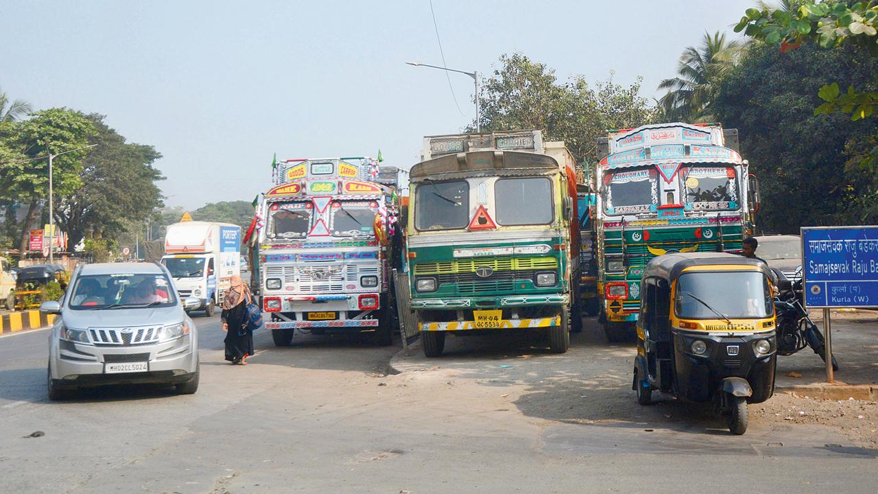 A woman walks on Lal Bahadur Shastri Marg as trucks are  parked on the pavement in Kurla