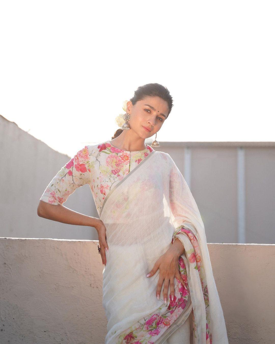 She paired it with a linen blouse that had a round neck, half sleeves, matching floral prints, front button closures, and a cropped hem.