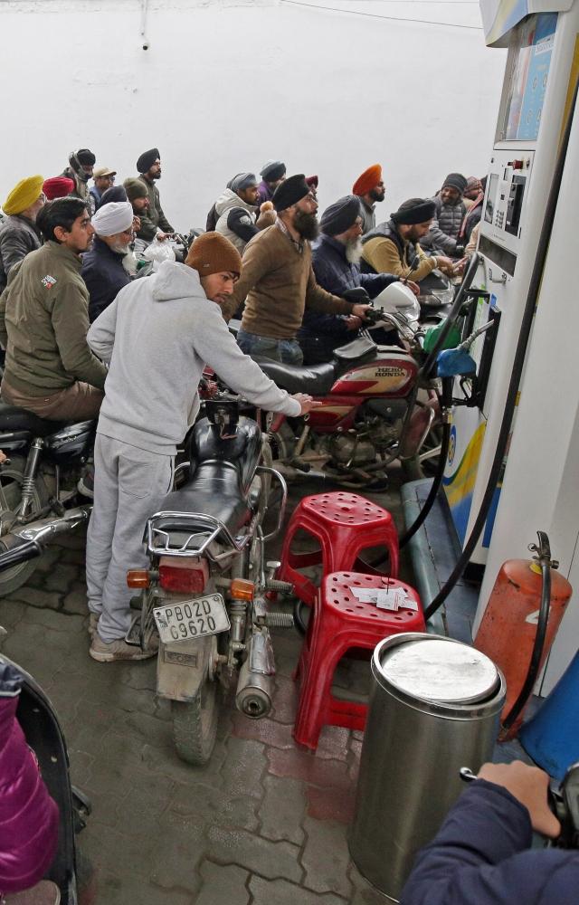 Commuters with their vehicles wait in long queues at a fuel station to refill their vehicle tanks in fear of shortage of fuel as truck drivers protest