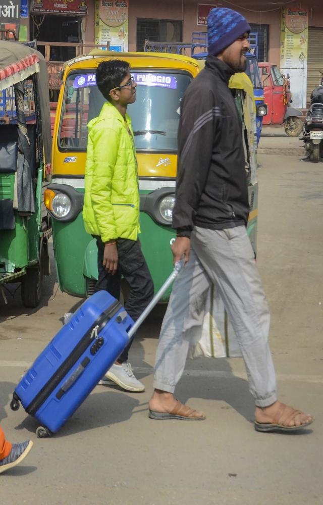 Passengers walk with their belongings as they try to reach their destination amid a strike of buses and trucks, in Ranchi, Tuesday, Jan. 2, 2024.