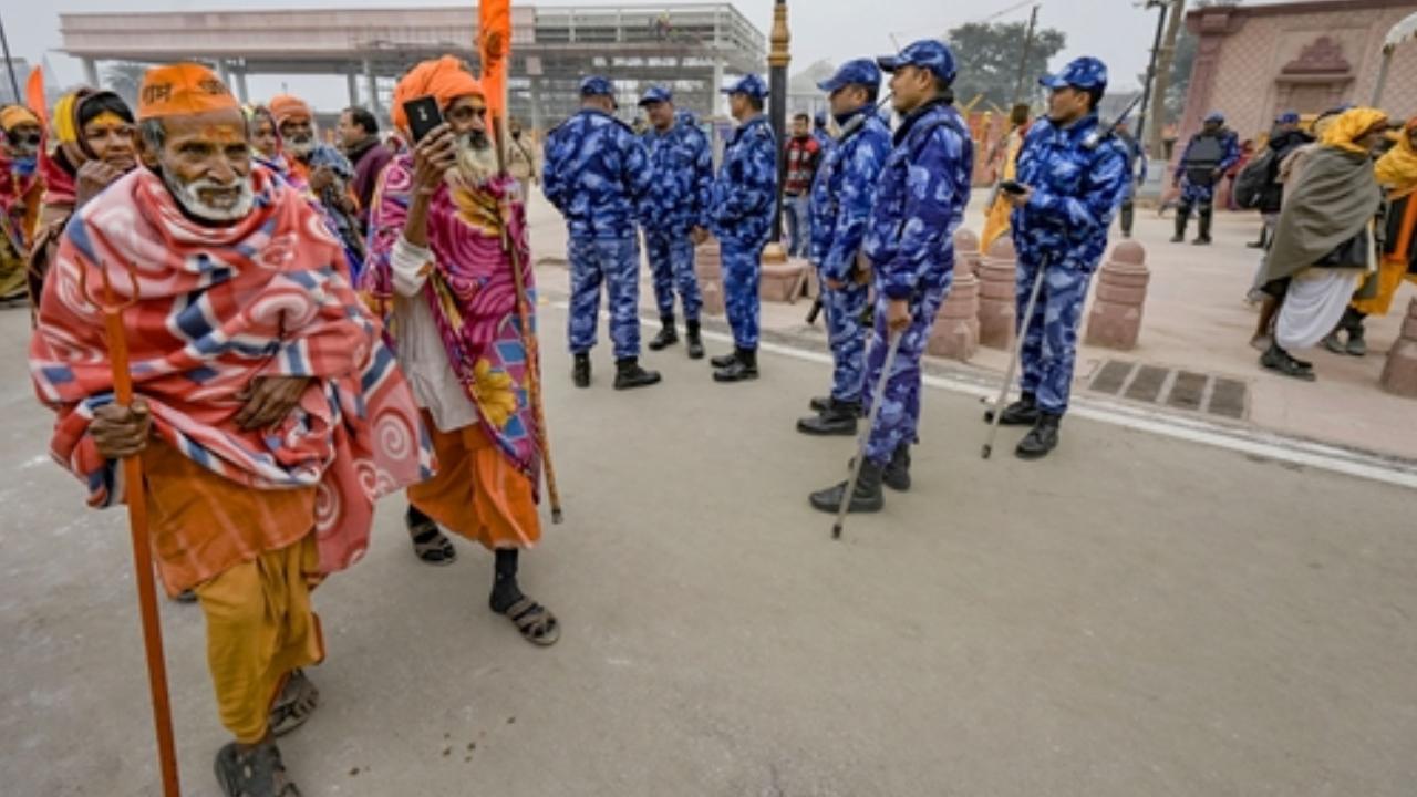 Devotees walk past security personnel on a cold winter morning on Friday