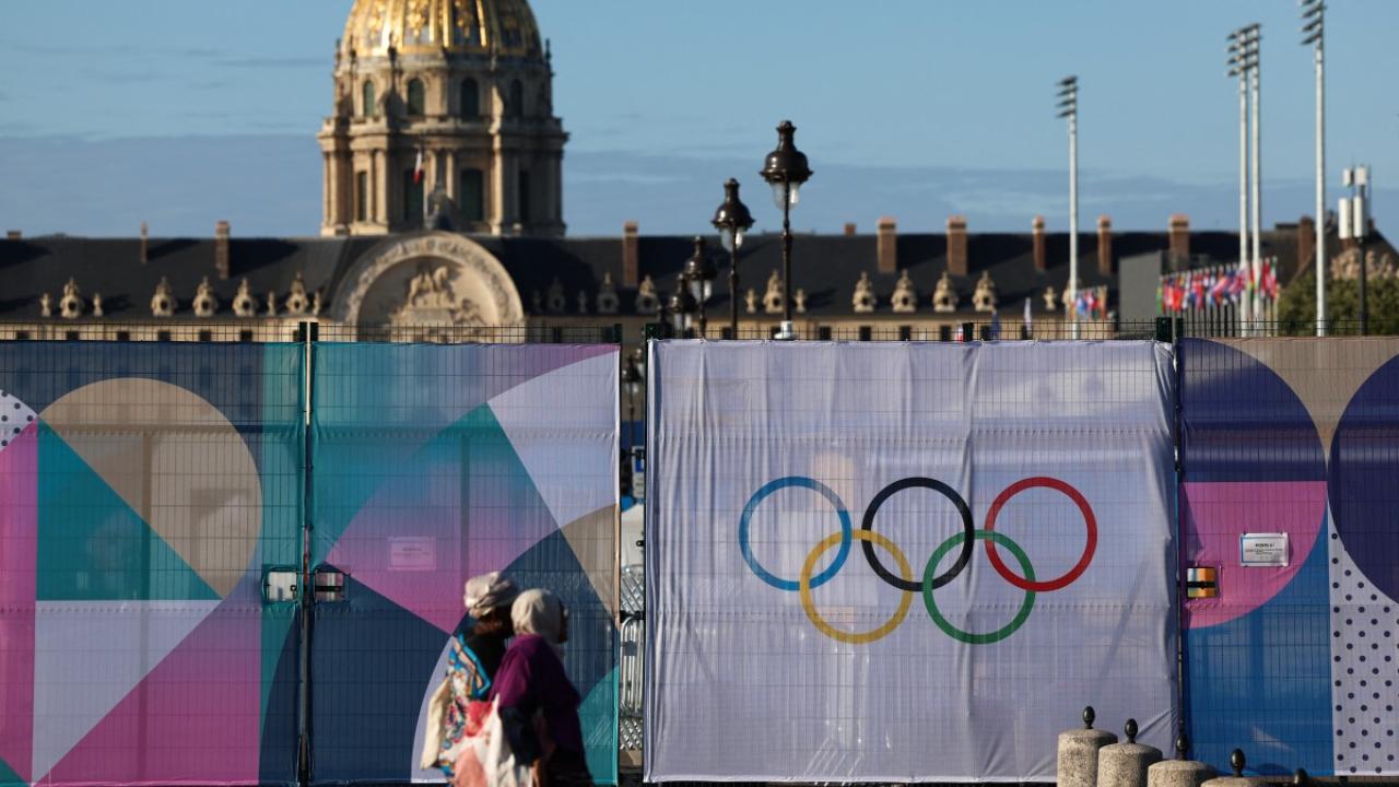 Pedestrians walk past the Hotel des Invalides Olympic site surrounded by fences displaying the Olympic rings ahead of the Paris 2024 Olympic and Paralympic Games
Finishing touches are being applied to the venues across the City of Light and thousands of athletes and officials are pouring in, while the weather has brightened up after months of rain. 