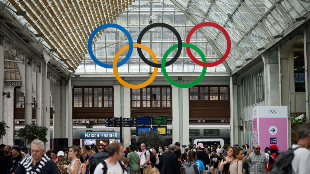 Commuters walk under the Olympic rings at the Gare de Lyon train station, on July 21, 2024, ahead of the Paris 2024 Olympic and Paralympic Games
It will be the first time a Summer Olympics has opened outside the main athletics stadium, with up to 300,000 ticketed spectators set to watch from stands and on the river banks and another 200,000 expected to watch from the overlooking apartments.