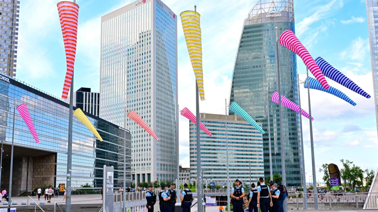 French Police officers stand guard on the Defense square (Place de La Defense) in Paris on July 21, 2024
The vast security operation for the opening ceremony is causing some friction with large parts of central Paris along the banks of the river and around Olympic venues off-limits for most people.  Trade groups representing Paris shops, restaurants, bars and clubs complained on Friday that they were facing an 