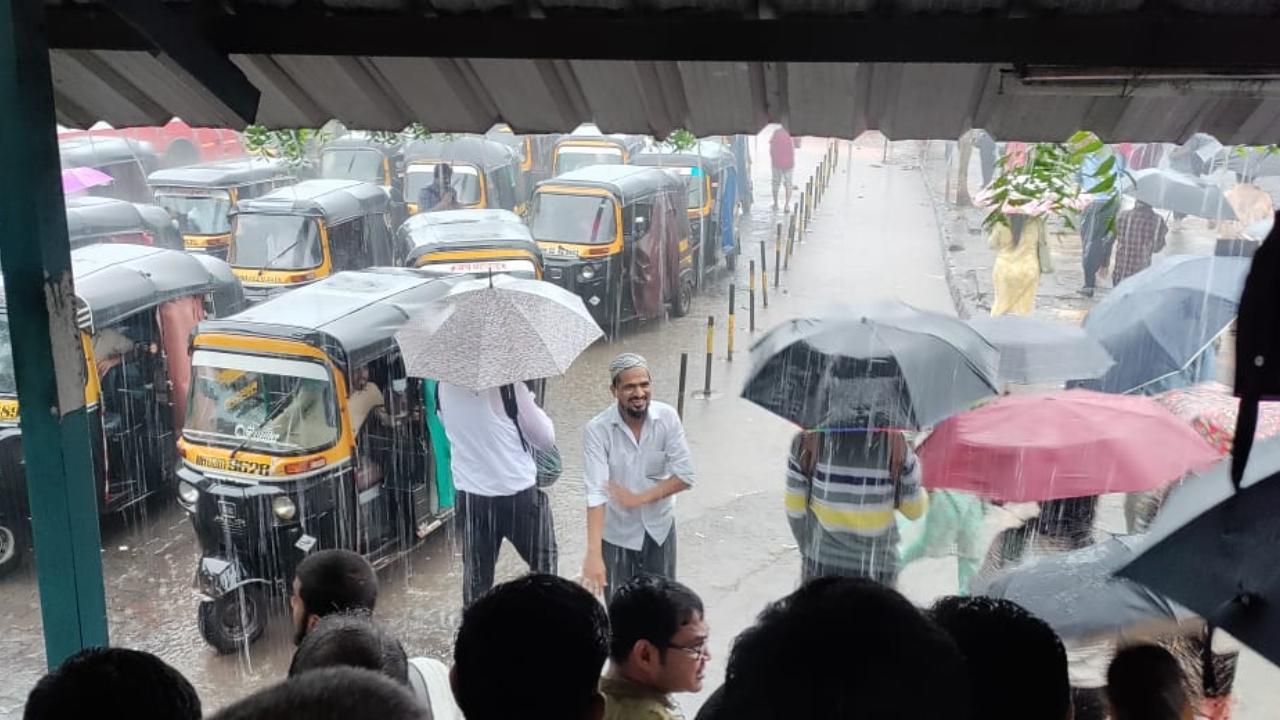 Mumbai's office-goers walk out of the exit at Bandra East railway station as they open their umbrellas to get out. Photos Courtesy: Nascimento Pinto