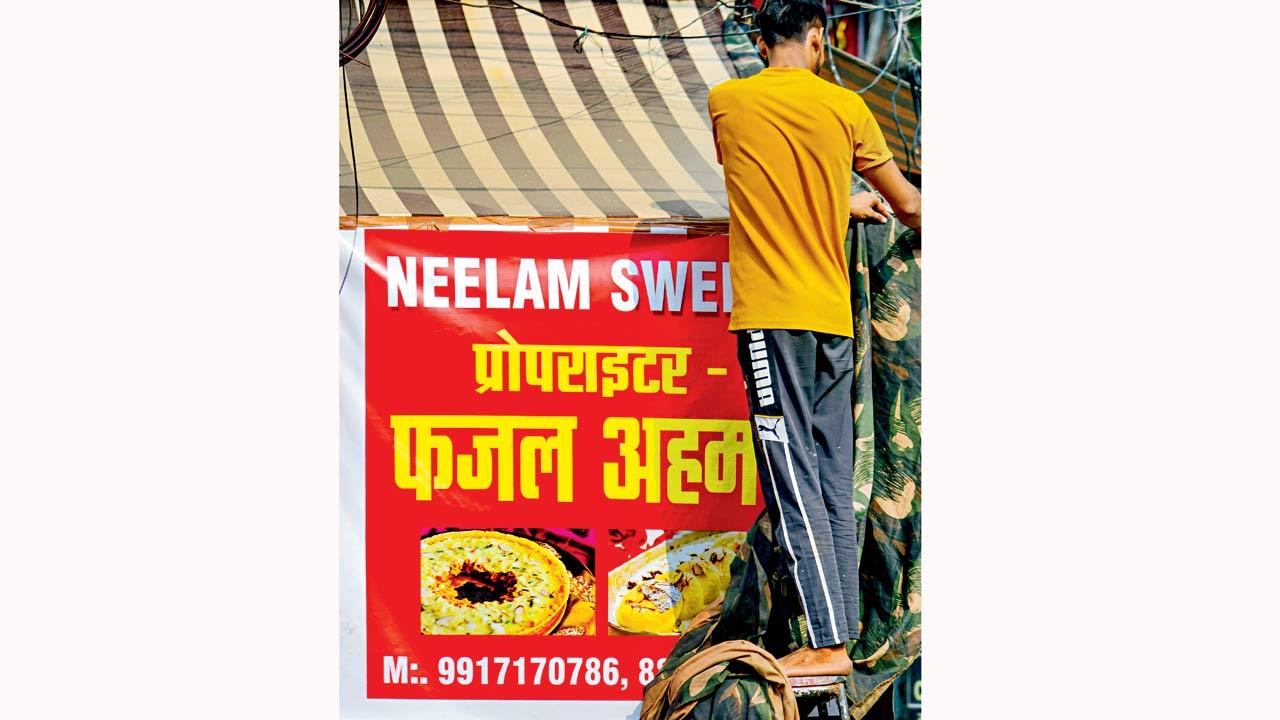 A banner with shopkeeper’s name being put up on a shop. Pic/PTI