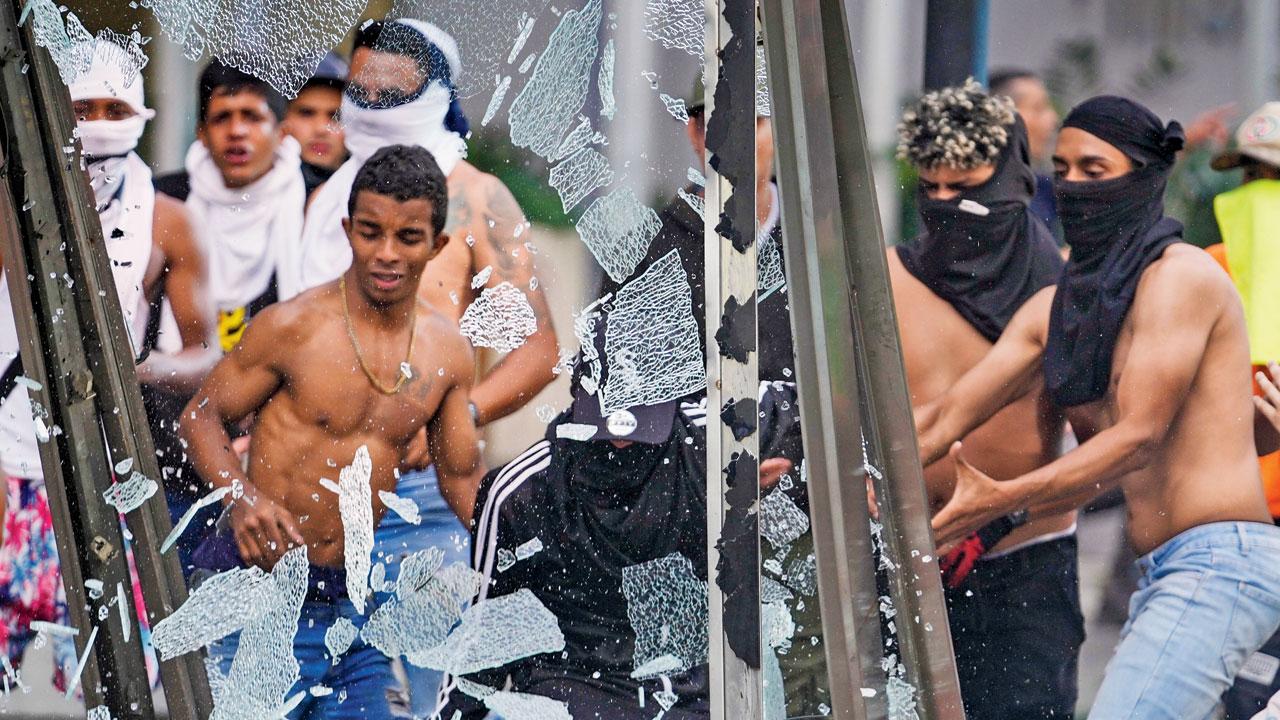 Smash an advertising board during violent demonstrations in Caracas, on Tuesday. Pics/PTI