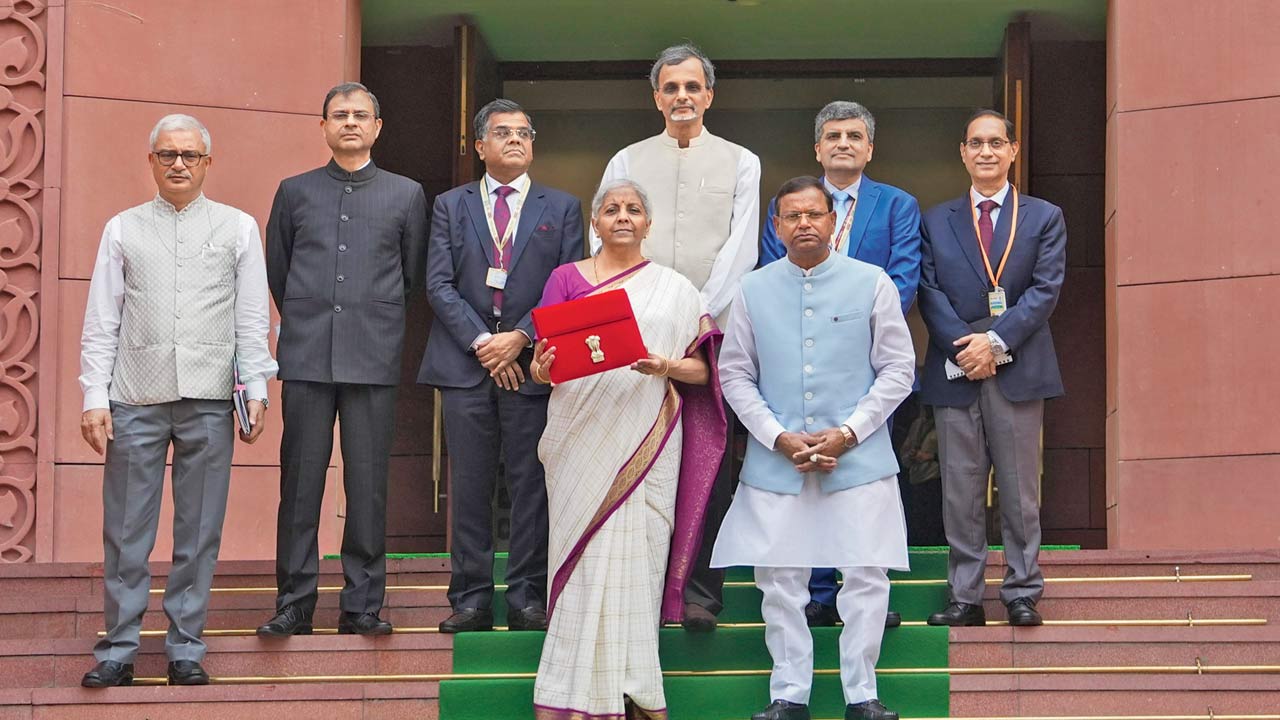Union Finance Minister Nirmala Sitharaman displays a red folder containing the Budget documents after she arrived at Parliament to present the budget with her team. Pics/PTI