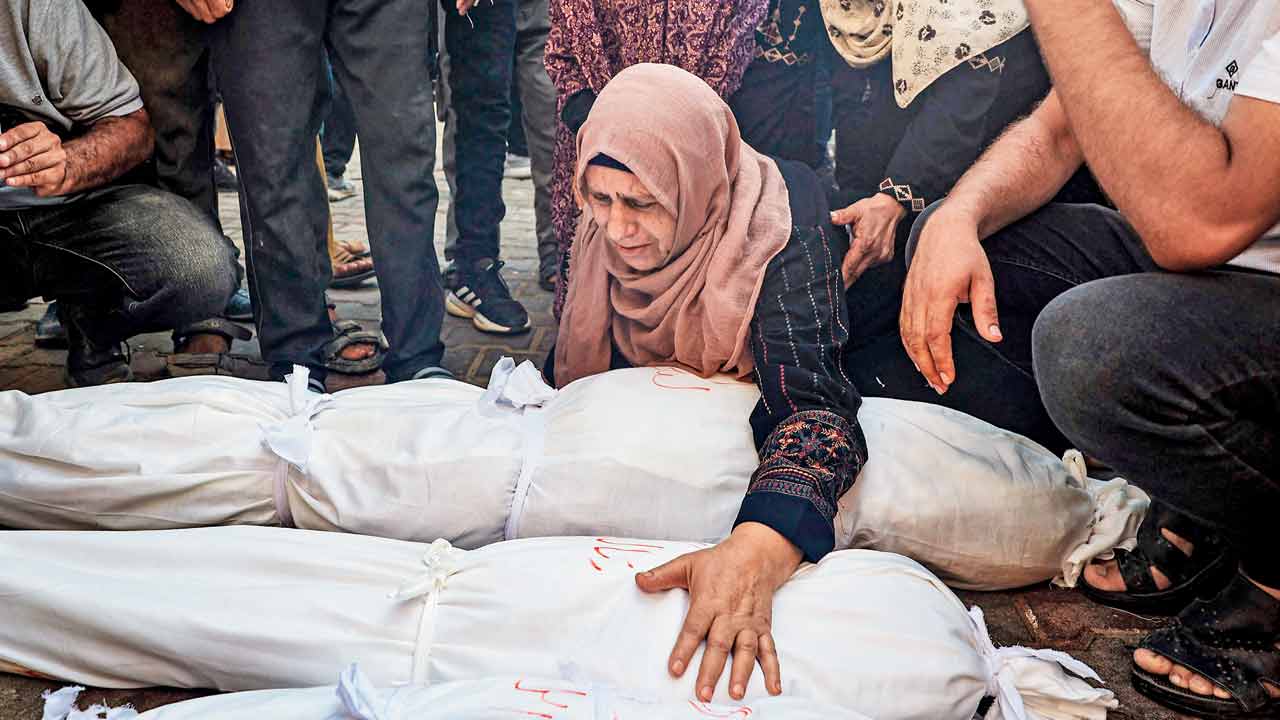 Palestinian women mourn over the shrouded bodies of three children killed in an Israeli bombing in Deir el-Balah. PIC/PTI