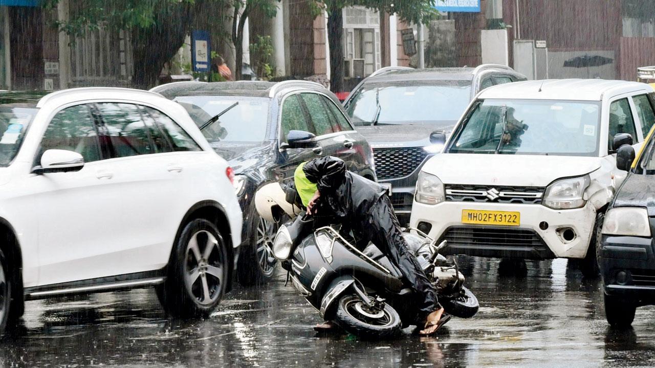 A biker loses balance in the middle of heavy rain after being hit by a car at a signal at Pedder Road. Pic/Sayyed Sameer Abedi