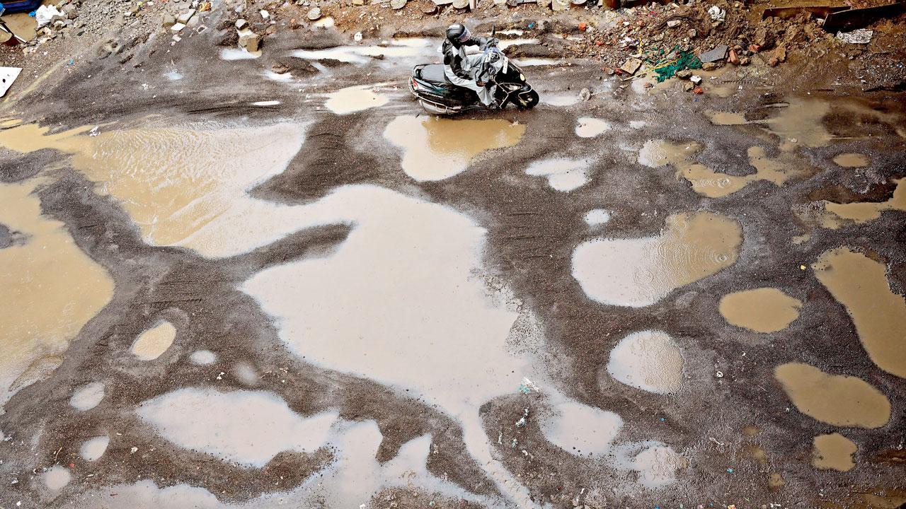 A scooter rider avoids huge craters outside Dadar station, on Monday. Pic/Shadab Khan