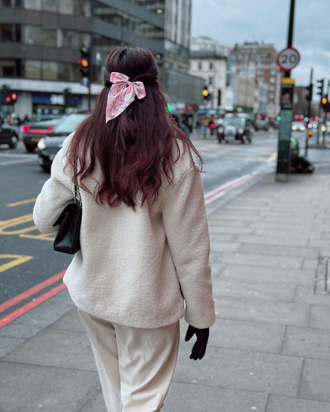 In this picture, Sana is seen wearing a white woollen outfit. She is tying her hair in a stylish hairstyle adorned with a bow