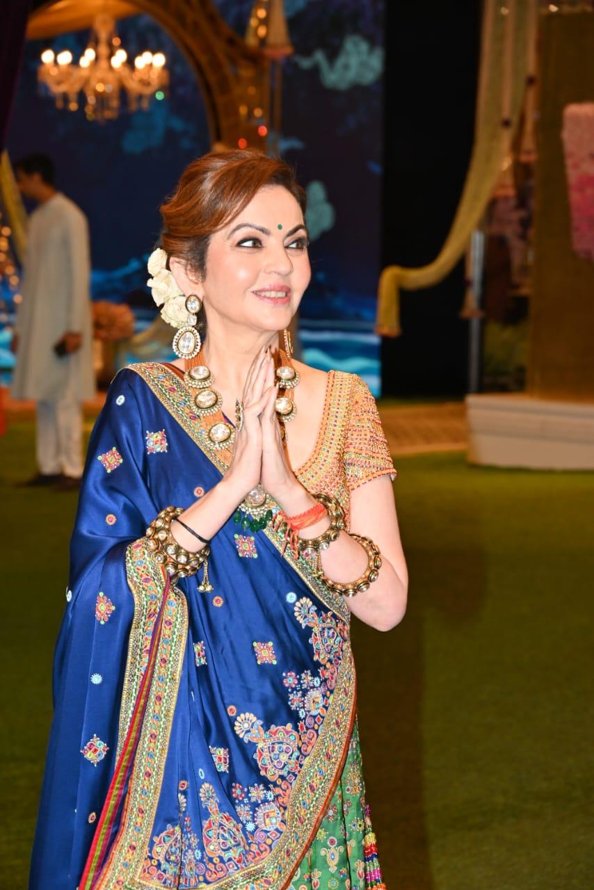 Nita Ambani wore a custom Tharad masterpiece lehenga in peacock emerald green with a gold blouse and a blue satin silk dupatta. The lehenga is paired with a gold jeweled blouse using chandan haar and silver thread
