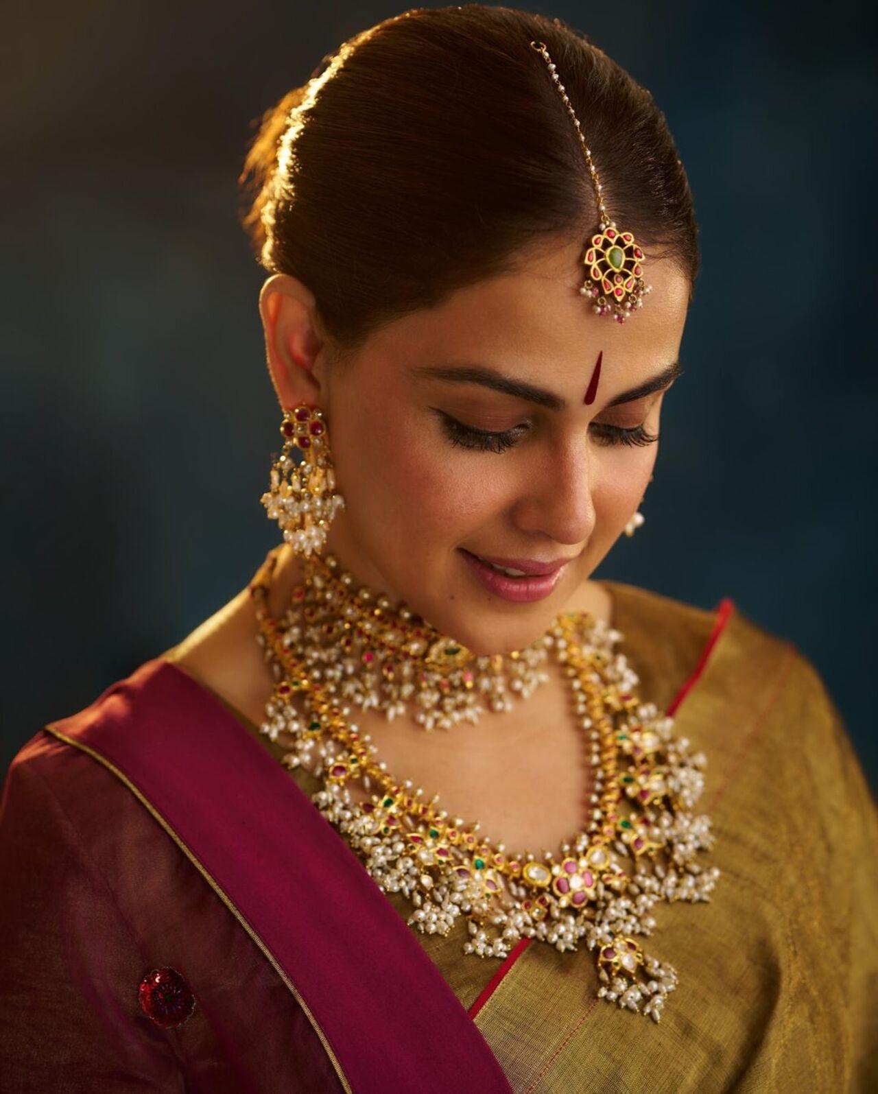 Genelia tied her hair in a chic bun and wore intricate jewelry, including two neck pieces, a pair of big earrings, and a beautiful maang tikka