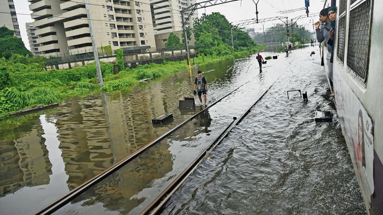 Commuters on railway tracks between Kurla and Sion due to heavy rain on Monday. File Pic/Atul Kamble