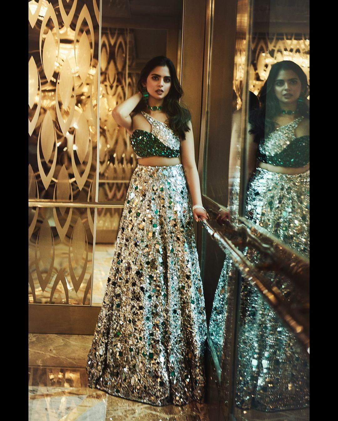 The choli was adorned with green and ivory stones throughout and had an asymmetrical front cut. The skirt, in silver, was embellished with mirrors and stones.