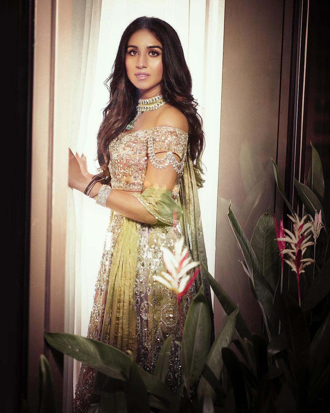 Her outfit was complemented by an off-shoulder blouse adorned with crystal embellishments and a dupatta draped elegantly around her arm.
