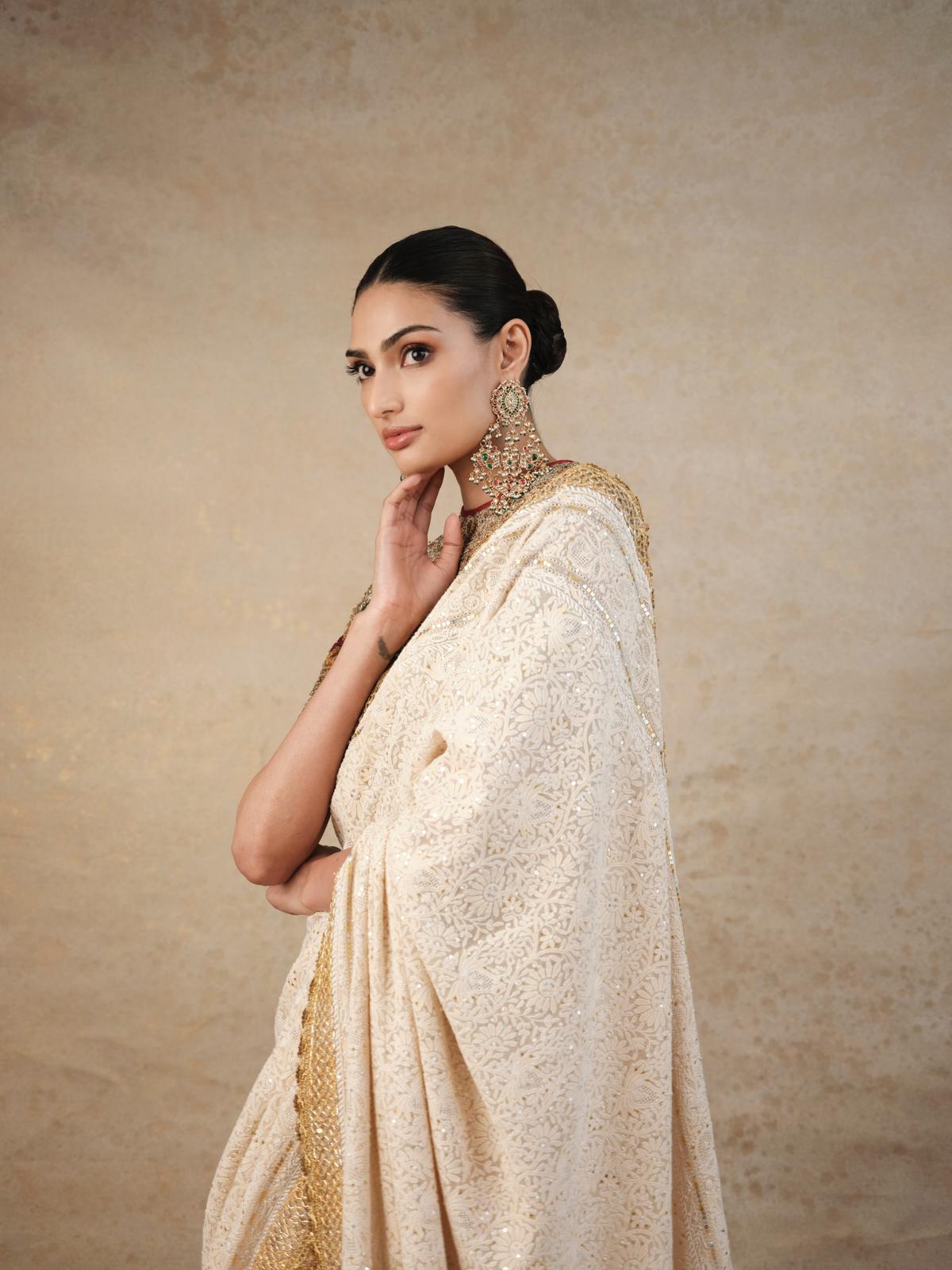 The striking golden-patti border added a nice touch to the ensemble. She paired it with a bandhgala blouse with half-sleeves, adorned with multicolored embellishments that beautifully complemented the saree.