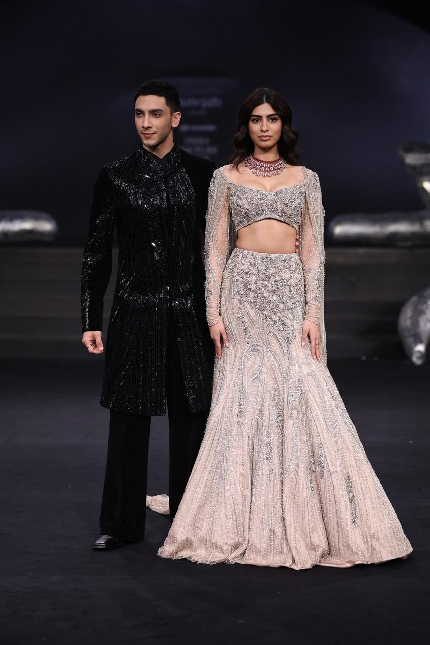 The show culminated with Khushi Kapoor and Vedang Raina as the showstoppers. Khushi donned a fitted mermaid skirt and an off-shoulder blouse with sleeves, paired with a shoulder cape. Her outfit, in a mesmerizing Sand hue, was adorned with thousands of dripping crystals, pearls, and Zardozi embroidery. Vedang wore a black velvet long jacket featuring intricate refraction embroidery.