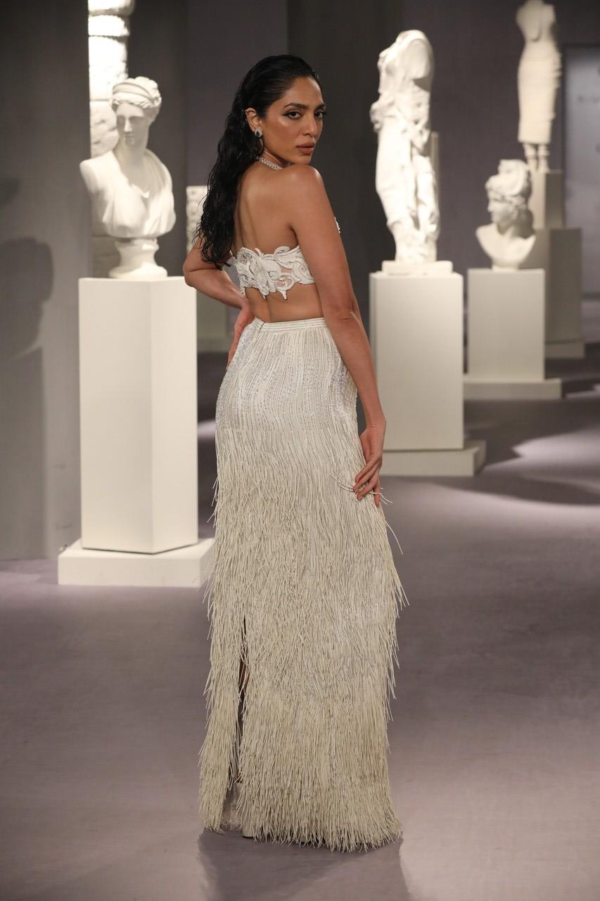 The 'Made in Heaven' star strutted down the ramp in an ivory ensemble. She looked stunning in an off-shoulder bralette that she paired with a glittery ivory fringe skirt with a floor-length hemline. Her outfit is inspired by an ostrich's flamboyance.
