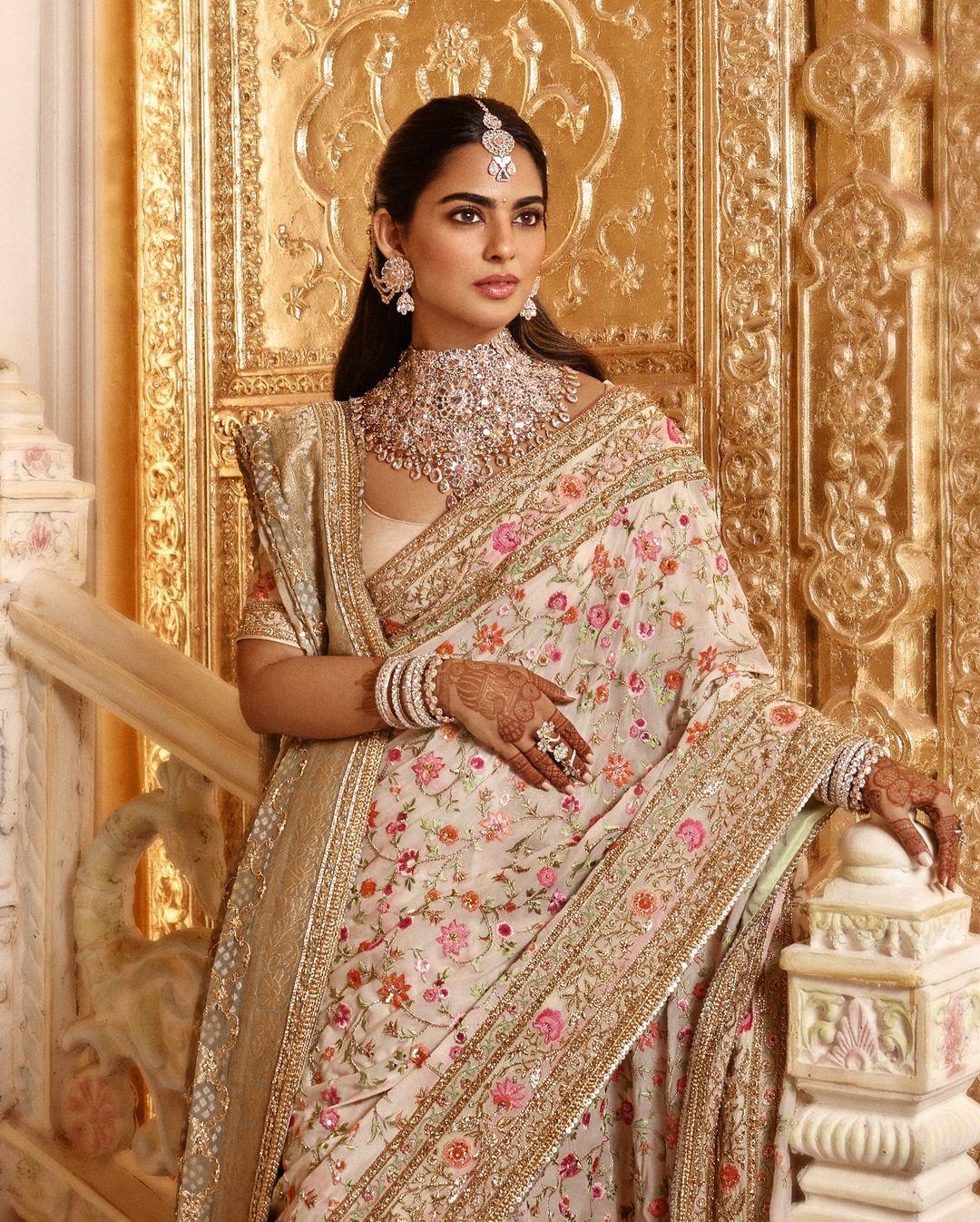 For Anant’s wedding, Isha looked stunning in a saree blending ivory and pink shades, decorated with intricate floral embroidery throughout. The border was delicately adorned in gold, and she complemented her outfit with a beautiful dupatta.