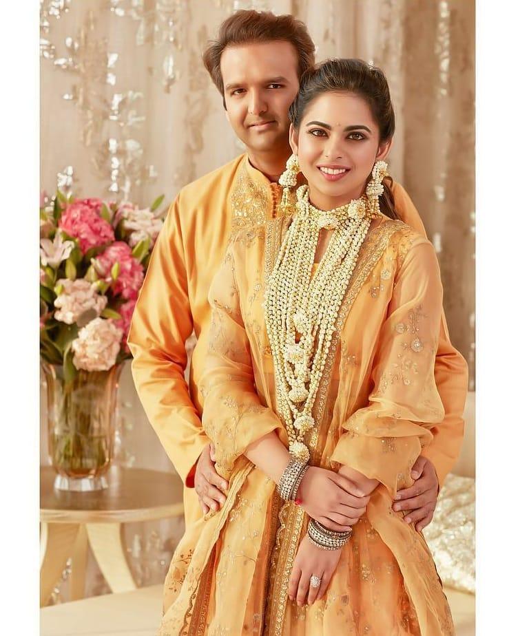 Haldi ceremony
If you followed Isha Ambani and Anand Piramal’s extravagant wedding, you might remember her Haldi ceremony ensemble. She opted for something different. She chose a peachy-yellow lehenga by Sabyasachi adorned with intricate gold threadwork, complemented by a matching organza dupatta. 