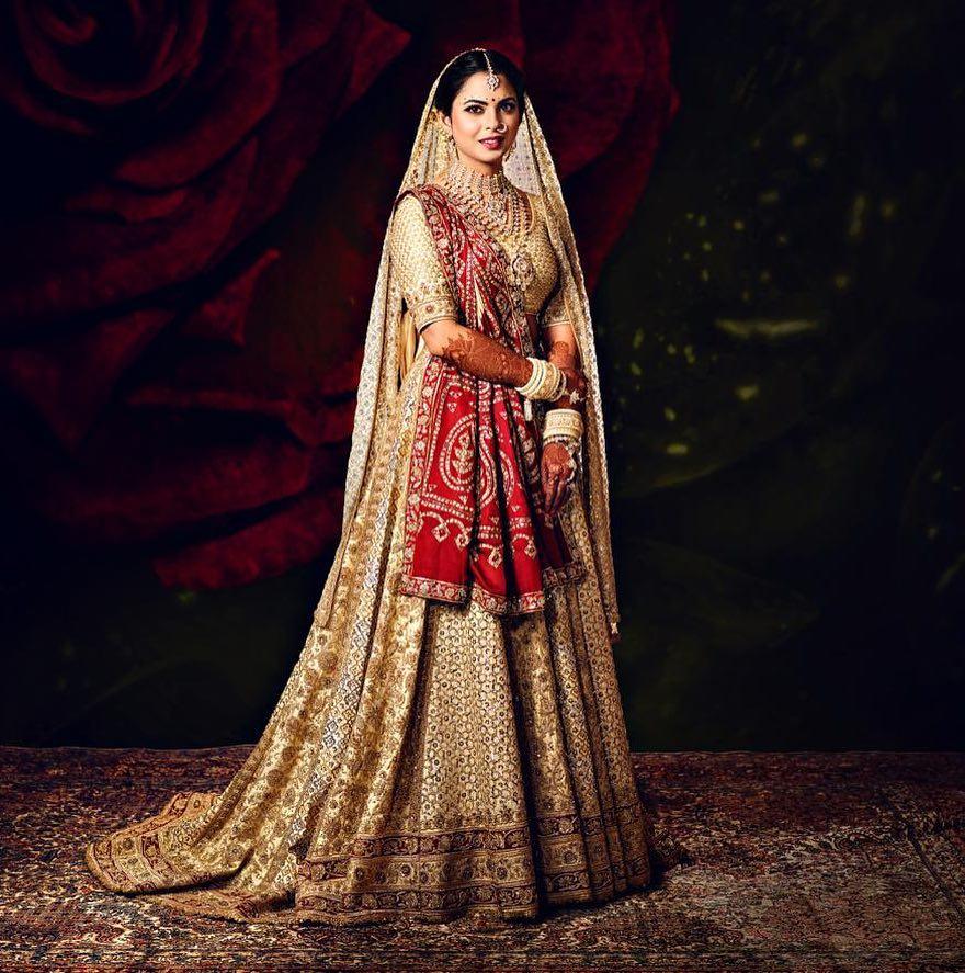 Wedding outfitFor her wedding, Isha Ambani opted for an ivory and gold ensemble designed by Abu Jani Sandeep Khosla, blending traditional and heritage elements. She wore a 16-paneled ghagra in two shades of off-white, featuring a trailing design. 