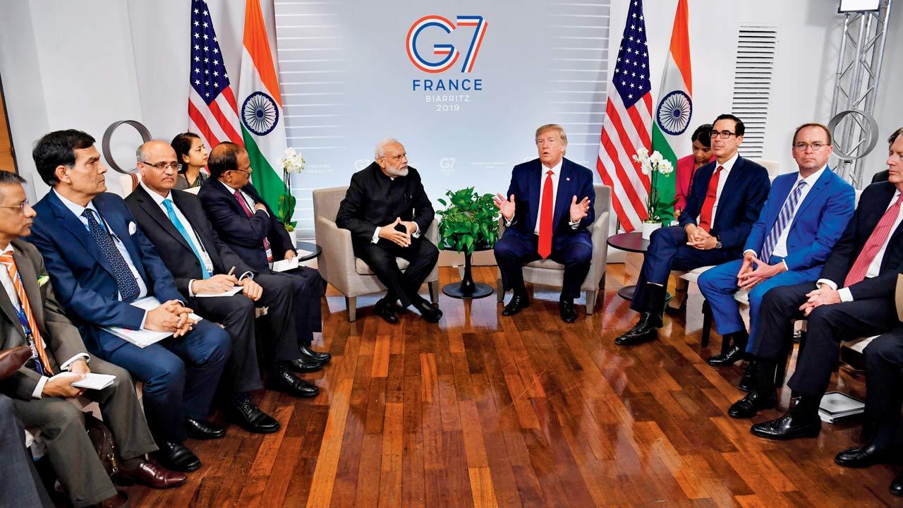 Prime Minister Narendra Modi and former US President Donald Trump speak  during a bilateral meeting in Biarritz, south-west France on August 26,  2019, on the third day of the annual G7 Summit. Gurdeep can be seen  working on the right, near the Indian flag